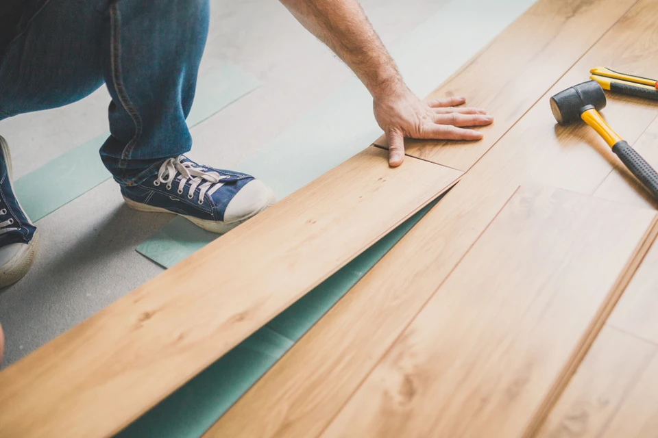 Intérieur résidentiel avec artisan installant du parquet flottant