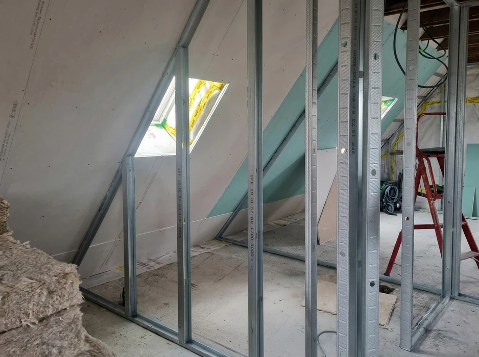 Chantier de combles aménagés en cours, ossature métallique en profilés d'acier galvanisé (montants SPF ID70) pour cloisons en plaques de plâtre type BA13 teintées vert