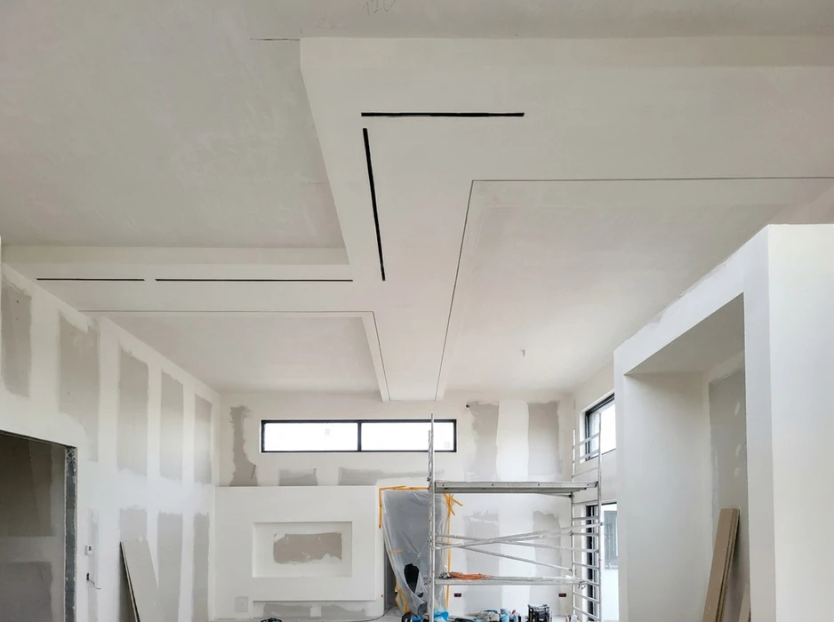 Chantier intérieur en cours de finition, vaste pièce lumineuse avec échafaudage métallique tubulaire
