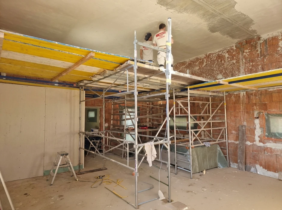 Deux ouvriers sur un échafaudage tubulaire aluminium intérieur effectuent un enduit de plafond