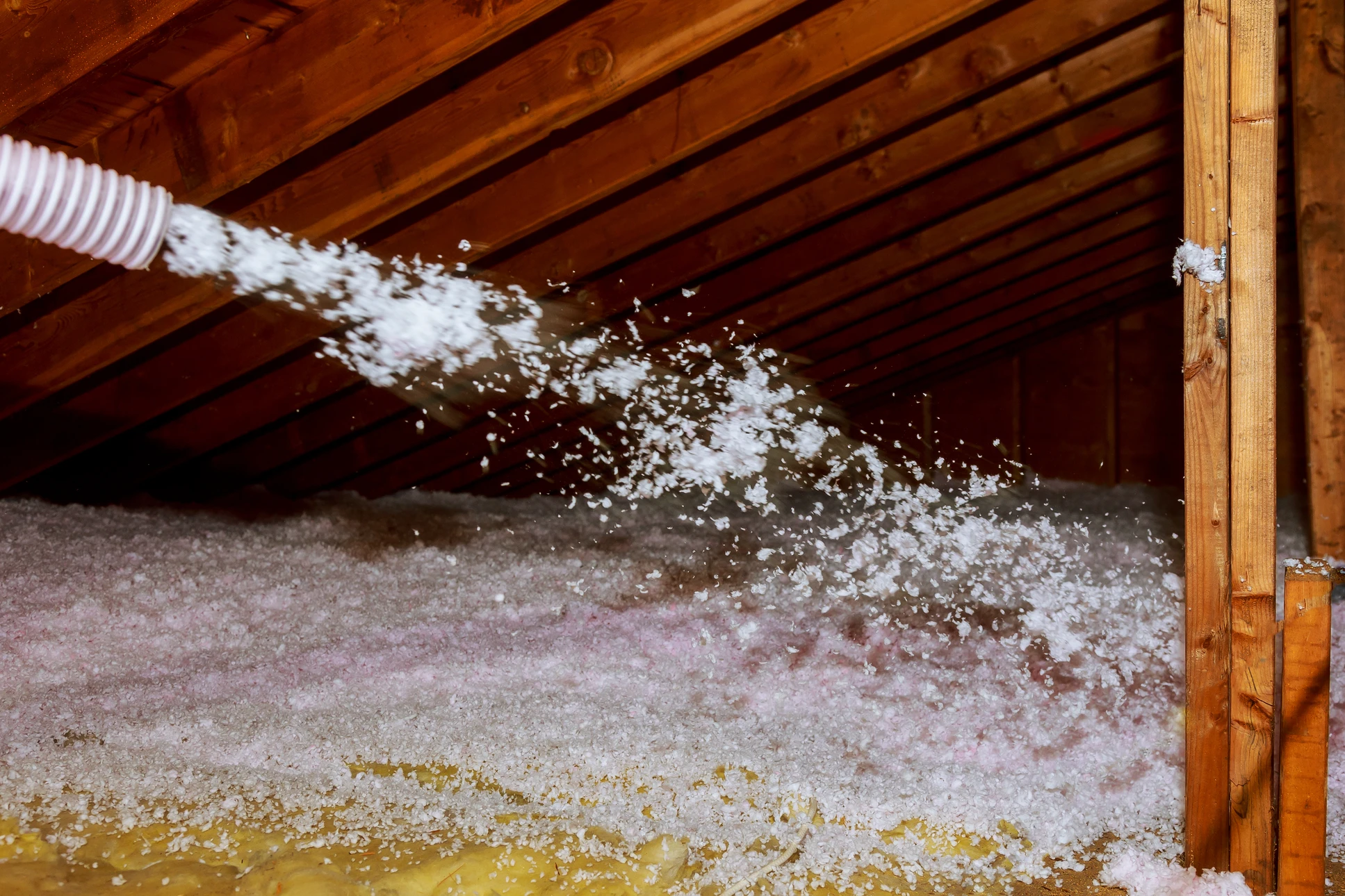 Grenier sous charpente en bois avec projection d'isolant en vrac par soufflage