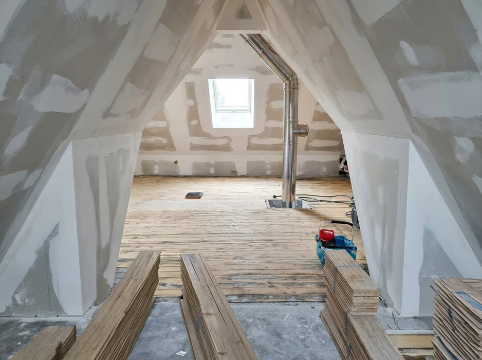 Chantier de rénovation intérieure, pièce allongée avec murs en pierre apparente et ossature métallique pour isolation