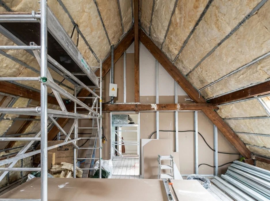 Intérieur d'un chantier de rénovation, vue depuis l'intérieur vers une fenêtre double vantail à cadre bois foncé