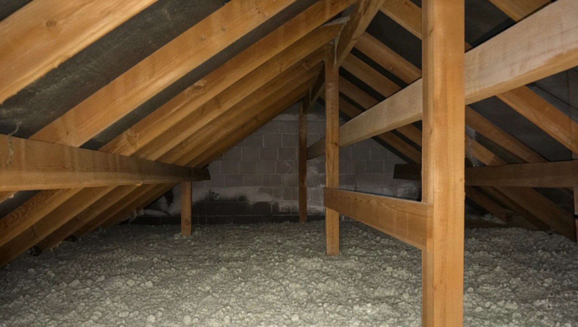 Ouvrier en salopette verte installant de l'isolant thermique en laine minérale entre solives de plancher en bois