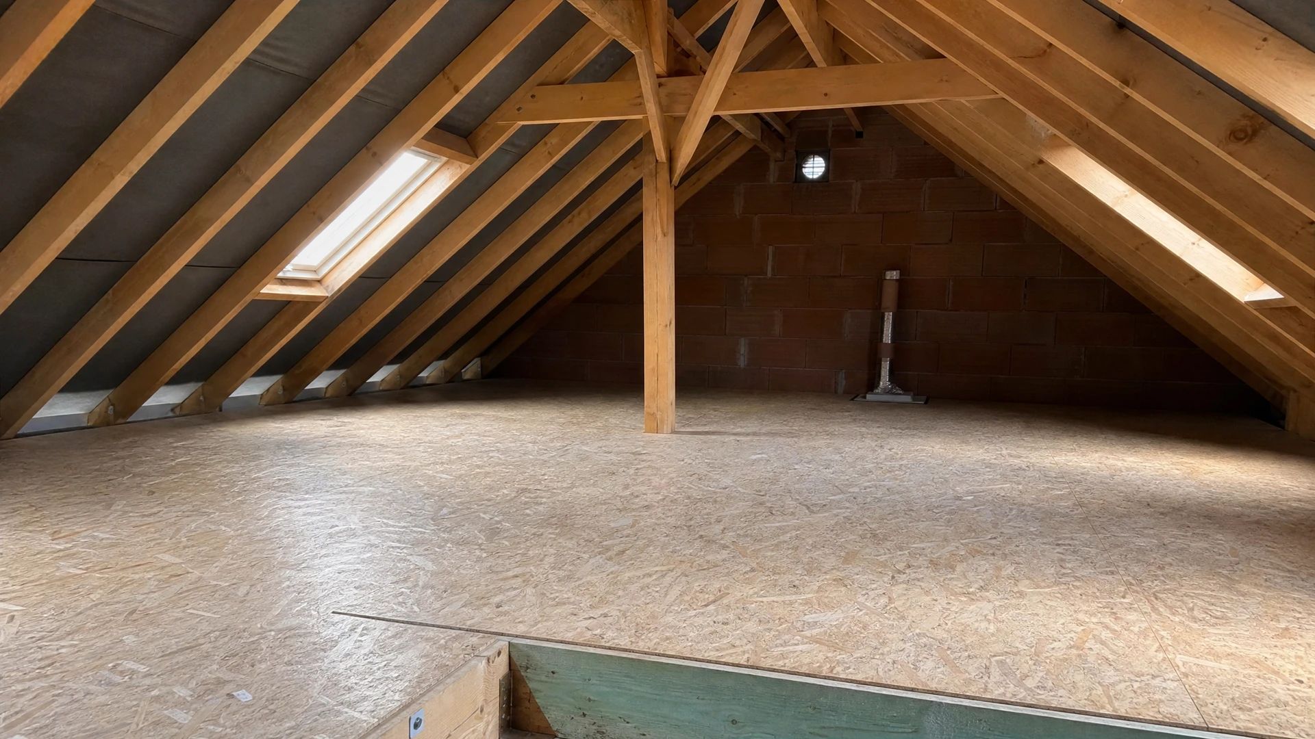 Travailleur en combinaison de protection intégrale avec masque respiratoire installe de l'isolation thermique dans combles